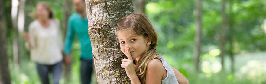 Mädchen hinter Baum versteckt sich vor Zecken.