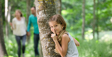 Mädchen hinter Baum versteckt sich vor Zecken.